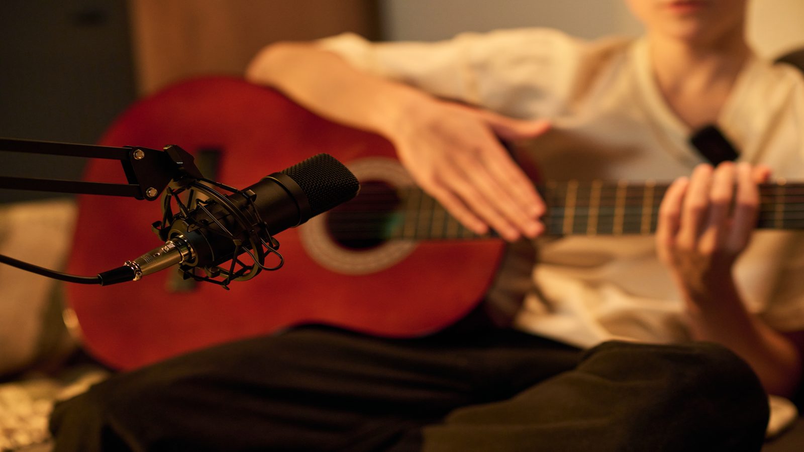 A close-up of a handheld recorder, wired headphones, and a notebook on a wood surface